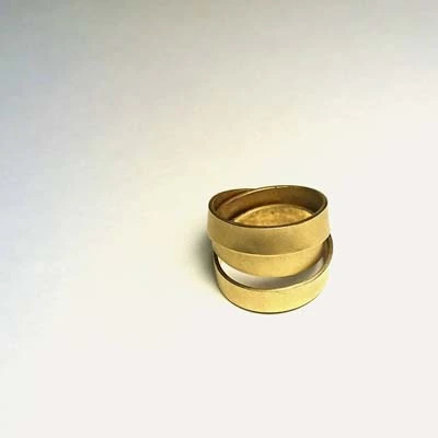 Bague anneau cylindrique large en métal doré sur fond clair