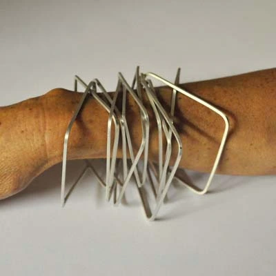 Accumulation de fins bracelets en jonc ondulés en argent au poignet