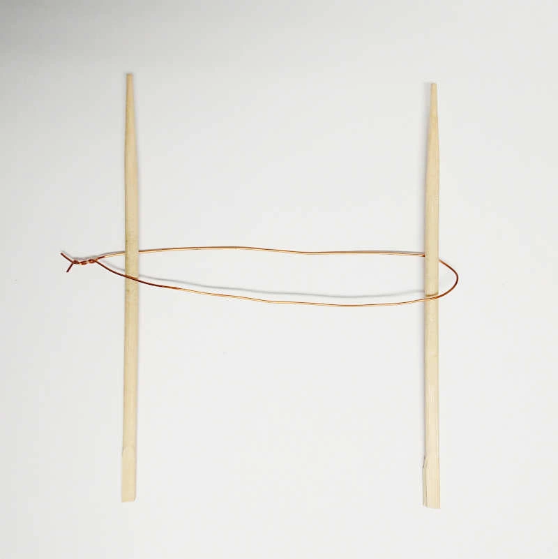 Deux baguettes tenant le fil de métal avant torsion